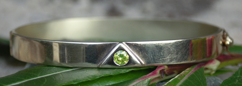 Zilveren Lemurië armband met in de driehoek een groene briljant ingelegd.