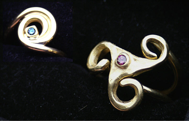Geel gouden ringen gebaseerd op de spiraal, een enkele (links) ingelegd met een blauwe diamant en rechts, een trikel met purple diamant ingelegd