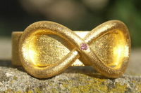 Zuiver gouden ring met lemniscaat motief en purple briljant.