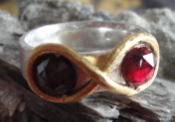 Zuiver zilveren ring met zuiver gouden lemniscaat, ingelegd met twee rode granaten