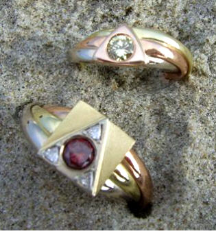 Twee driekleur gouden ringen: één met rode briljant en 3 triljanten ingelegd, de ander met een groene briljant.